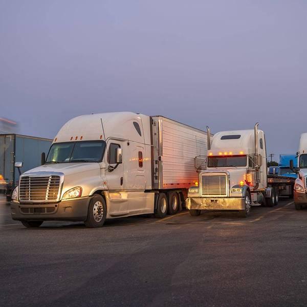 A row of parked semi-trucks with their headlights on.