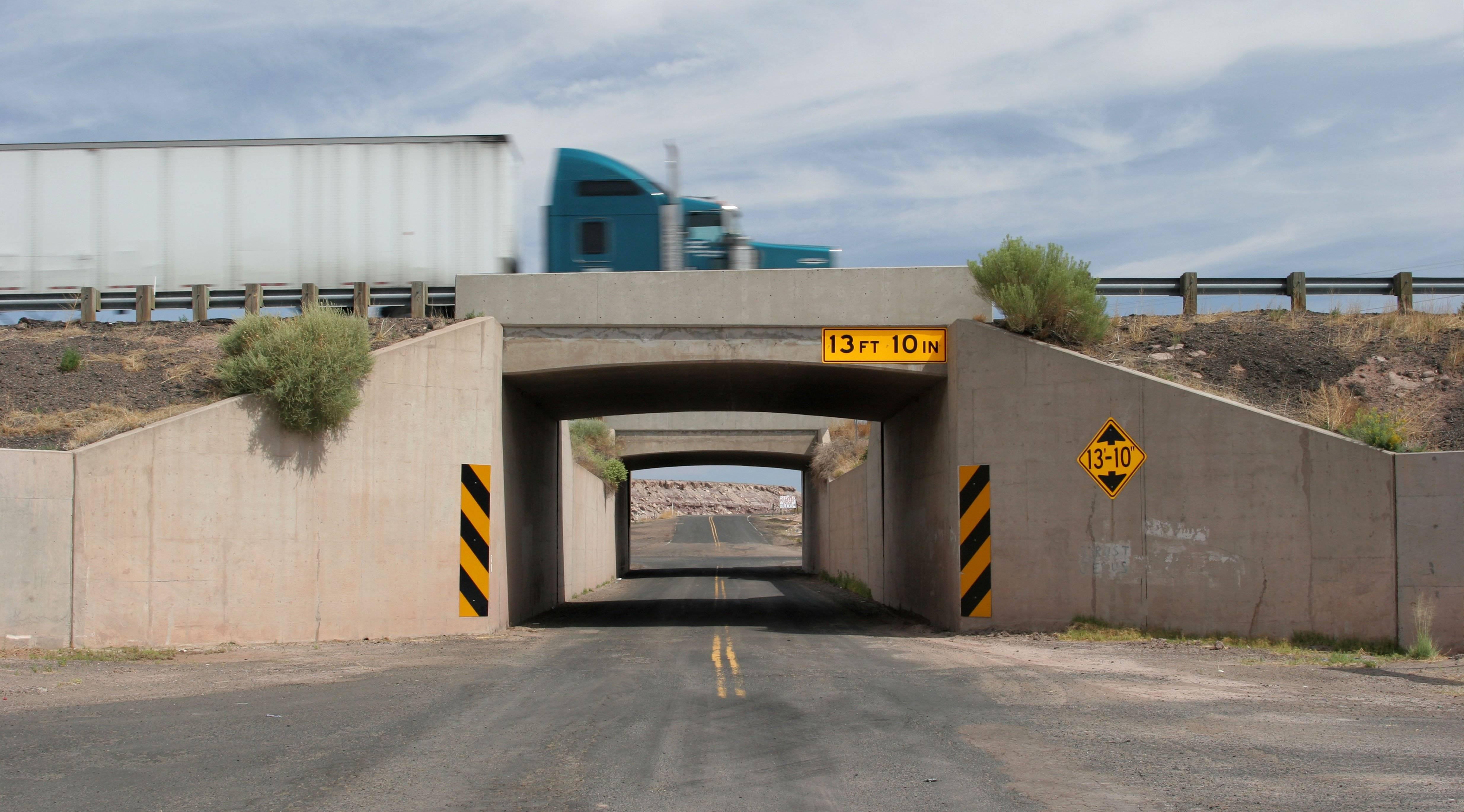 A semi truck drives over a bridge with a clearance of 13 feet, 10 inches.
