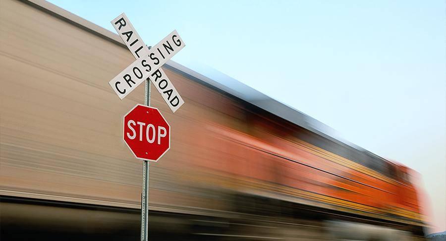 A train in motion passing a railroad crossing and stop sign.