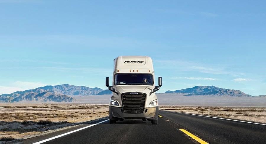 A white Penske truck on the road