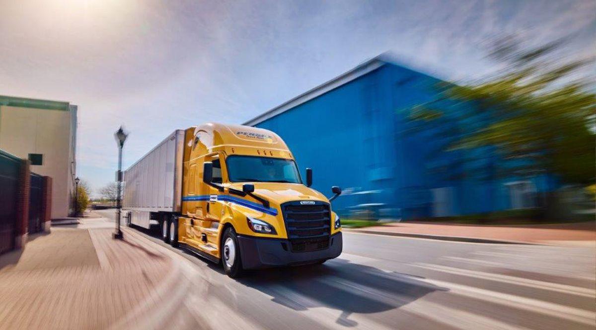Yellow Penske tractor with trailer drives up a road.